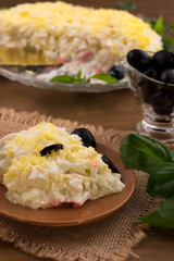 Beautiful salad with eggs, cheese, crab meat, decorated with chopped marinated olives and basil  leaves.