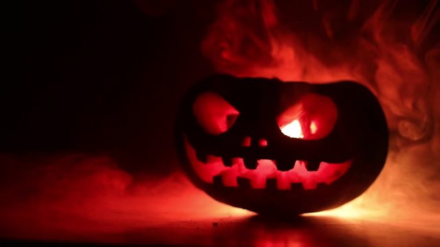 Halloween pumpkin smile and scrary eyes for party night. Close up view of scary Halloween pumpkin with eyes glowing inside at black background. Selective focus