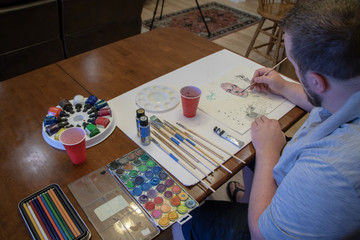 Over the should of an artist painting a watercolor