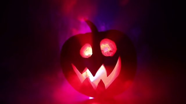 Halloween pumpkin smile and scrary eyes for party night. Close up view of scary Halloween pumpkin with eyes glowing inside at black background. Selective focus