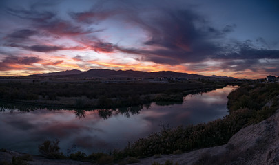Fototapeta na wymiar Banner panorama of a dark sunset with clouds reflecting off the river
