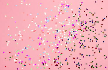 Festive pastel pink background with metallic confetti.