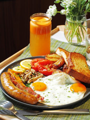 English breakfast with fried eggs, bacon, sausages, beans, toasts and salad on the plate 