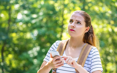 Young woman using her smartphone on a bright summer day in the forest