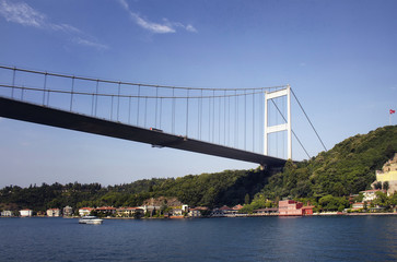 View of a yacht, FSM bridge, Bosphorus and buildings on Aisan side of Istanbul. It is a sunny summer day.