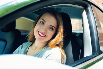 Happy young woman in a new luxury car