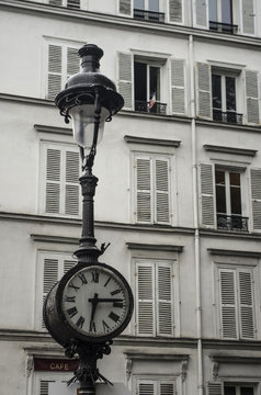 Clock and streetlight old and typical of Paris in Montmartre with a French flag at a window