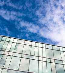 blue sky and clouds reflected in windows of modern building