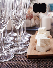 Sliced Feta cheese on beautiful wooden coasters against the background of champagne glasses