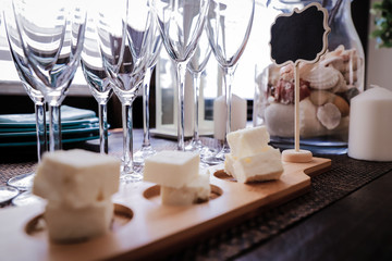 Sliced Feta cheese on beautiful wooden coasters against the background of champagne glasses