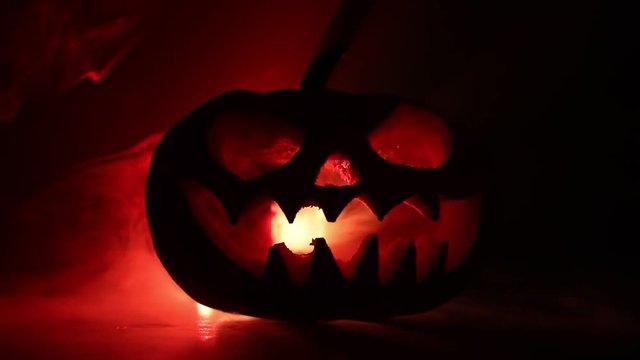 Halloween pumpkin smile and scrary eyes for party night. Close up view of scary Halloween pumpkin with eyes glowing inside at black background. Selective focus