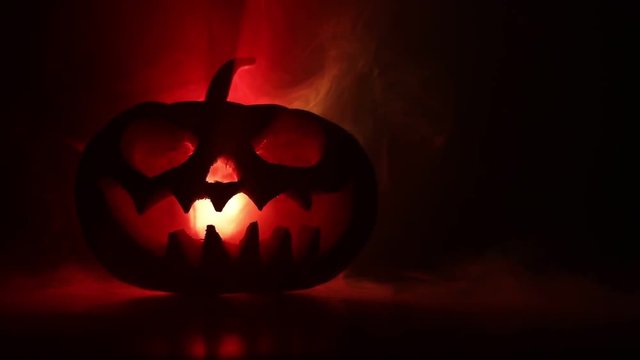 Halloween pumpkin smile and scrary eyes for party night. Close up view of scary Halloween pumpkin with eyes glowing inside at black background. Selective focus