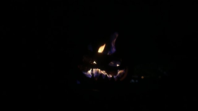 Halloween pumpkin smile and scrary eyes for party night. Close up view of scary Halloween pumpkin with eyes glowing inside at black background. Selective focus