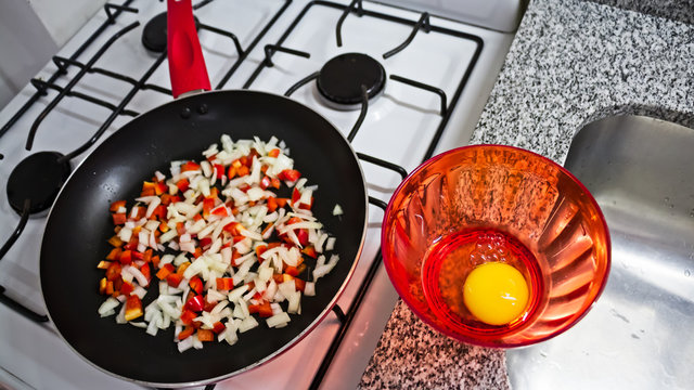 Yema de huevo y sarten en cocina blanca