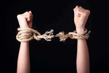 Unrecognizable person getting free is raising arms showing a frayed rope