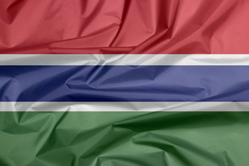 Fabric flag of Gambia. Crease of Gambian flag background, red blue and green color and separated by a narrow band of white.