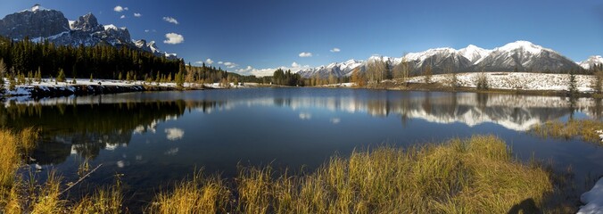 Wide Panoramic Landscape of Blue Quarry Lake and Snowy Rocky Mountain Peaks above City of Canmore near Banff National Park Alberta Canada