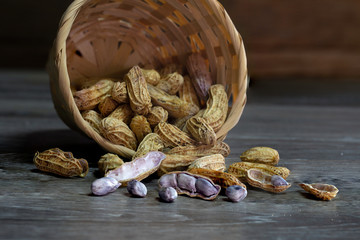 Peanut boiled seed falling from bamboo basket on wooden ground dim light