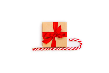 Christmas sledge - a gift box over candy cane on a white background. Abstract christmas concept.