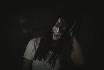 Asian female zombie standing in dark room and looking at camera