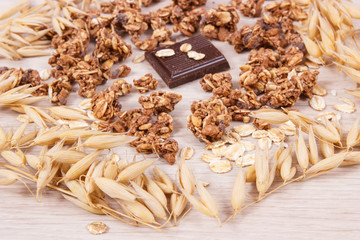 Ears of oat, flakes, granola and chocolate containing iron and fiber, healthy snack concept