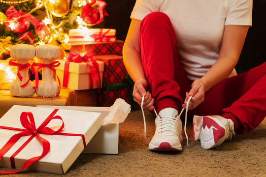 Woman In Pajamas Ties The Laces Of Athletic Shoes. Christmas Present. Birthday Present.