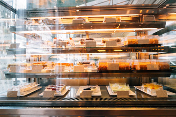 Many assortments of sweet dessert cakes being displayed and decorated in cafe restaurant.