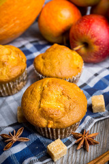 Homemade atutumn muffins with pumpkin, apples and spices on the rustic background. Selective focus. 