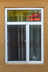 An open window with a mosquito net in the wall of the house