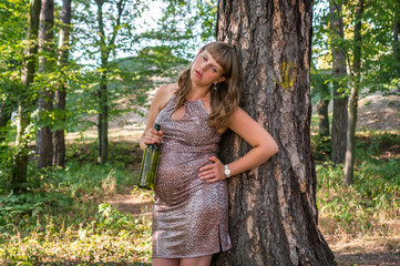 Pregnant woman drinking wine in the park - alcoholism concept