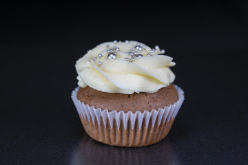 Fragrant, vanilla capcake with berry filling and honey cream cheese on black background