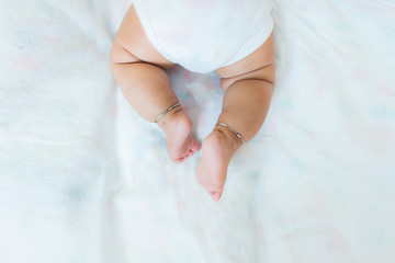 Baby legs on the bed, soft focus newborn tiny feet, lower body.