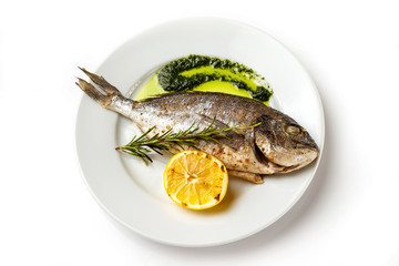 Top view image of plate with fresh grilled dorado fish and lemon isolated at white background.