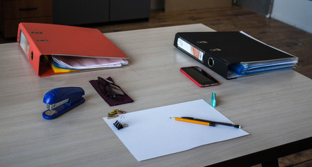 a desk with paper pencils phone calculator glasses