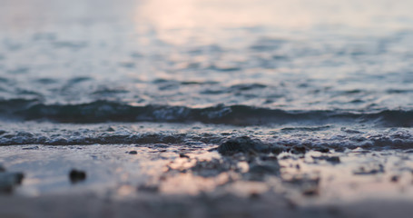 Sea waves over sand beach at sunset time