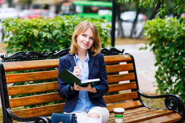 Young woman studying and writing in a park.