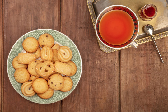 An Overhead Photo Of Danish Butter Cookies On A Plate, On A Dark Rustic Background With A Cup Of Tea On A Vintage Tray, With Jam, And A Place For Text