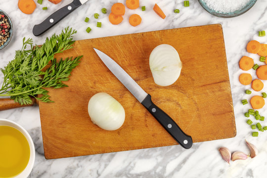 Prep time, or mise en place. An overhead photo of a professional chef's knive, shot from above on a cutting board, with chopped vegetables and spices, on a marble cooking surface with copy space