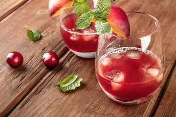 A closeup photo of vibrant red drinks with cherries on a dark rustic background