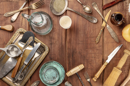 An overhead photo of many vintage kitchen objects and cutlery from an old restaurant, flea market stuff on a wooden background with copy space