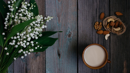 a Cup of tea, nuts, bouquet of lilies on a wooden table