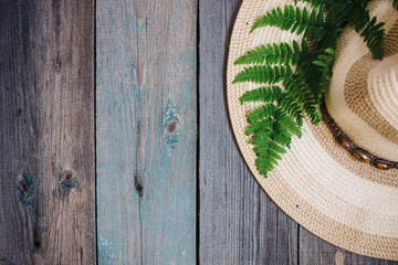 a hat, a fern leaf on the wooden background, copy space