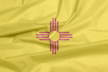 Fabric flag of New Mexico. Crease of New Mexico flag background, The states of America, The red and yellow of old Spain. The ancient Zia Sun symbol in red.