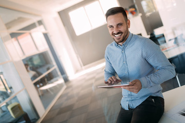 Happy young businessman holding tablet in office