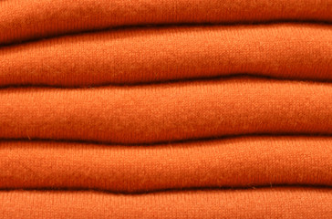 Fototapeta na wymiar Stack of trend Russet Orange woolen sweaters close-up, texture, background