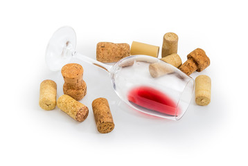 Glass lying on its side with wine among of corks
