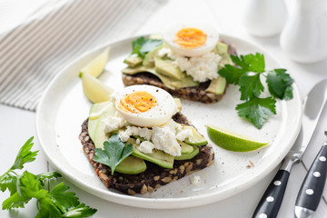 Whole grain toast with avocado, egg, white cheese. Closeup view