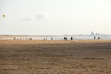 Fototapeta na wymiar People are walking on a sunny day along the beach in Katwijk. Netherlands