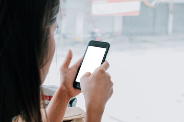 Woman relaxing while using smartphone blank screen for graphics display montage. Over the shoulder view of