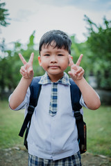 Happy children go back to school.Asian smiling boy with two fingers up going to school for the first time.